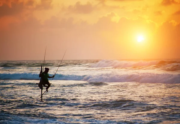 Silhouette of fisherman on sunset with beautiful dramatic sky — стоковое фото