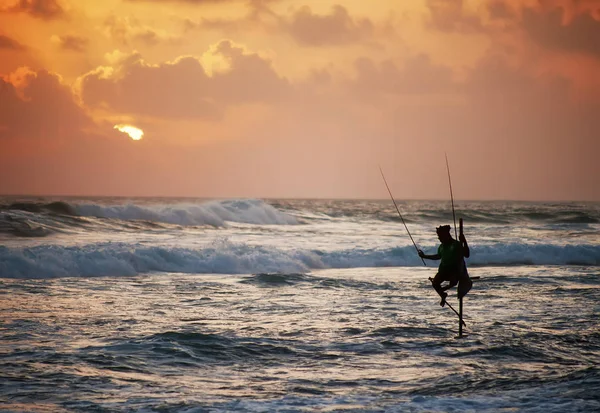 Silhouette of fisherman on sunset with beautiful dramatic sky — стоковое фото