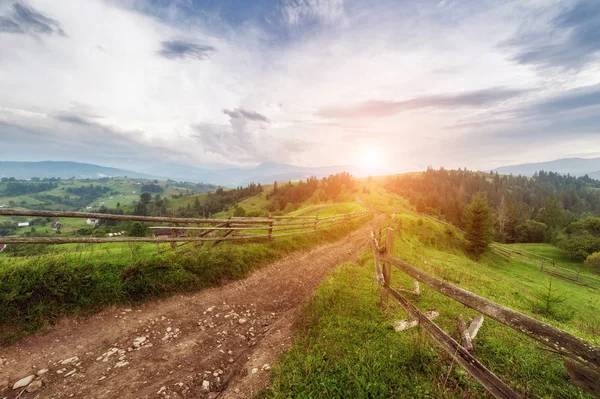 Vieille clôture en bois, route rurale et sommet de la montagne à l'horizon sur — Photo