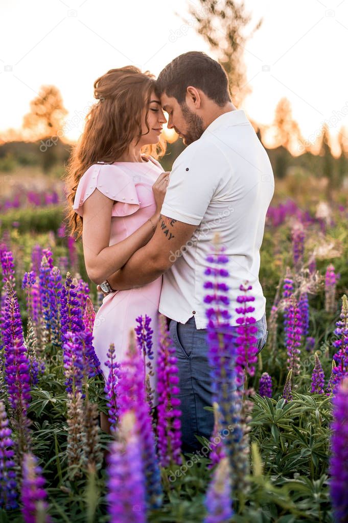 Happy romantic couple hugging in field of lupines