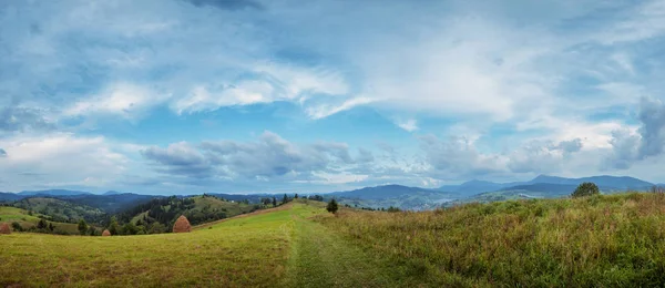 Meule de foin au sommet de la montagne et ciel nuageux incroyable. été rural — Photo