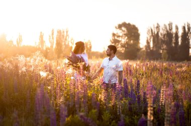 Lupines alanında el ele yürüyen mutlu romantik çift