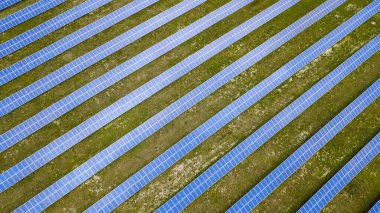 Yeşil çimenlikteki güneş panellerinin havadan görünüşü. İHA atışı, kuş gözü.