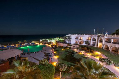 Egzotik okyanusun kıyılarında açık havuz ve suda palmiye ağaçlarının yansıması. Yaz manzarası. Gece manzarası.