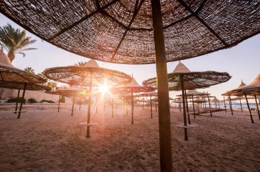 Egzotik tatil beldesinde kumlu denizde (okyanus) saman şemsiyeler. Yaz manzarası