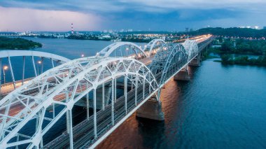 Hava gece şehir manzarası, aydınlık binalar ve köprü. İHA atışı.