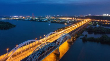 Hava gece şehir manzarası, aydınlık binalar ve köprü. İHA atışı.