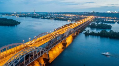 Hava gece şehir manzarası, aydınlık binalar ve köprü. İHA atışı.