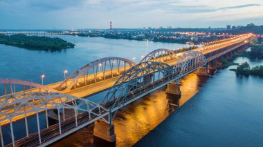 Hava gece şehir manzarası, aydınlık binalar ve köprü. İHA atışı.
