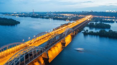 Hava gece şehir manzarası, aydınlık binalar ve köprü. İHA atışı.