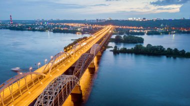 Hava gece şehir manzarası, aydınlık binalar ve köprü. İHA atışı.