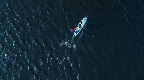 aerial shot of man on sup board in blue ocean