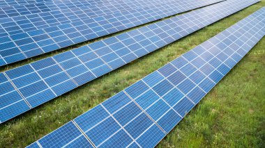 Yeşil çimenlikteki güneş panellerinin havadan görünüşü. İHA atışı, kuş gözü.