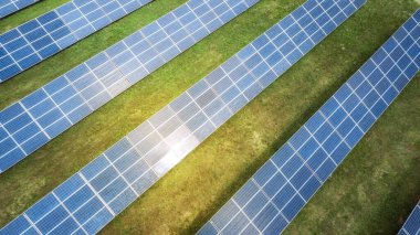 Yeşil çimenlikteki güneş panellerinin havadan görünüşü. İHA atışı, kuş gözü.