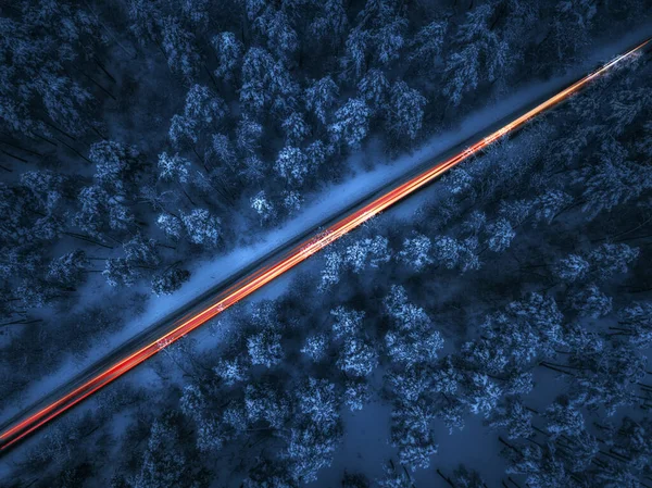 Gece manzaralı kış yolu ve dağlardaki ormandan geçen arabalar. İHA atışı