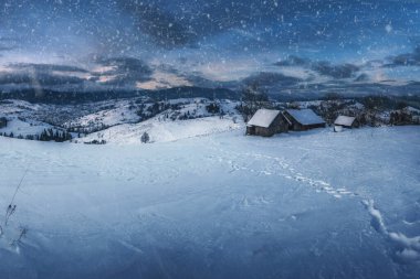 Kırsal köyün muhteşem panoramik manzarası ve gün batımında karla kaplı ufuktaki dağlar. Güzel kış manzarası