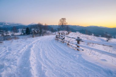 Kış manzarası. Kırsal yol karla kaplı. ufuktaki dağlar