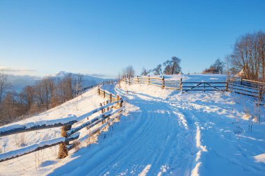 Kış manzarası. Kırsal yol karla kaplı. ufuktaki dağlar