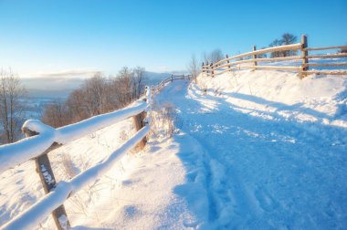 Kış manzarası. Kırsal yol karla kaplı. ufuktaki dağlar