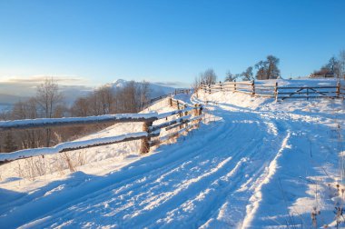 Kış manzarası. Kırsal yol karla kaplı. ufuktaki dağlar
