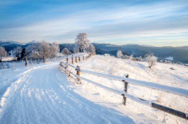 Kış manzarası. Kırsal yol karla kaplı. ufuktaki dağlar