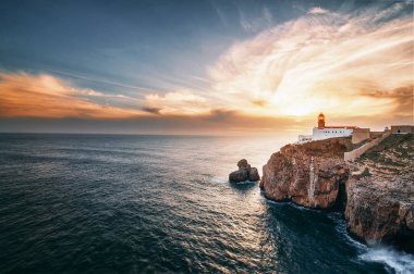 Atlantik Okyanusu manzaralı güzel bir ufuk. Gün batımında deniz feneri, kaya ve dalgalar. Algarve, Portekiz