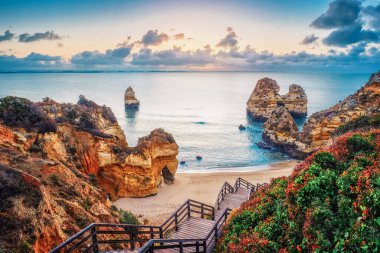 güzel Atlantik Okyanusu görünümü ufuk ile kumlu plaj, kayalar ve güneş doğarken dalgalar. Algarve, Portekiz