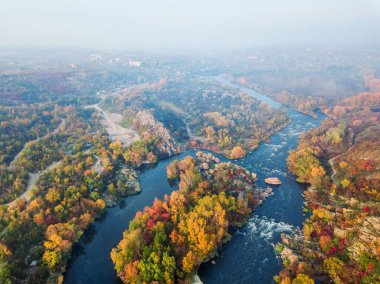 Renkli ormanın, mavi nehrin ve kayaların insansız hava aracı görüntüsü. Güzel sonbahar manzarası