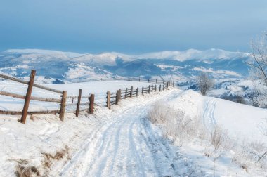 Kırsal kış yolu ufukta karla ve dağlarla kaplıydı. Güzel kış manzarası