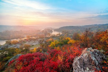 Güzel sonbahar manzarası, renkli ağaçlar ve gün batımında sisli bir nehir. 