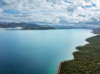 Mavi Adriyatik denizi, kumlu plaj, yeşil ağaçlar, temiz gök mavisi göl manzarası.