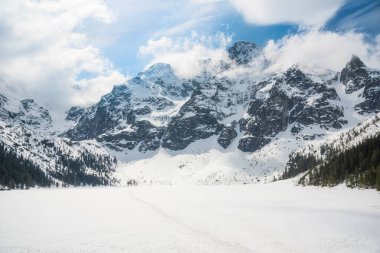 Polonya 'nın Tatra Ulusal Parkı' ndaki Morskie Oko 'nun sakin manzarası, görkemli karla kaplı dağlar, sakin donmuş göl ve serin bir kış günü yansımaları. Kış manzarası