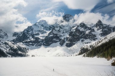 Polonya 'nın Tatra Ulusal Parkı' ndaki Morskie Oko 'nun sakin manzarası, görkemli karla kaplı dağlar, sakin donmuş göl ve serin bir kış günü yansımaları. Kış manzarası