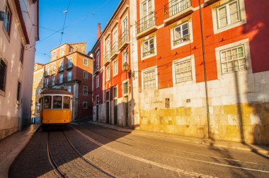Güneş batarken Lizbon, Portekiz 'in dolambaçlı sokaklarında dolanan büyüleyici sarı bir tramvay rotayı çevreleyen tarihi mimariyi vurguluyor.