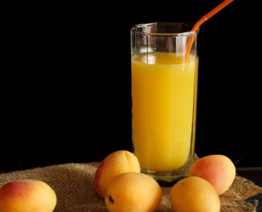 Bir bardak portakal suyu siyah arka planda kayısılı çuval bezi..