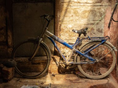 Varanasi, Uttar Pradesh, Hindistan - Şubat 2015: Eski şehrin pis bir köşesinde park etmiş mavi bir bisiklet.