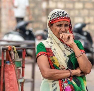 Somnath, Gujarat / Hindistan - 11 Aralık 2018: Renkli, geleneksel bir sari giymiş bir kadının samimi sokak portresi, antik Hindu hacı kasabasında bir geçit töreninin geçişini izler..