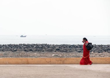 Somnath, Gujarat, Hindistan - Aralık 2018: Sari giyen Hintli bir kadın Somnath kasabasında deniz kenarında tek başına yürüyor.