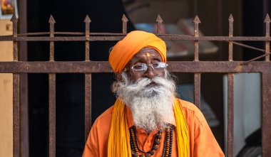 Somnath, Gujarat, Hindistan - Aralık 2018: Yüzünde düşünceli bir ifadeyle safran bornoz ve türban giymiş yaşlı bir Hindu keşişin samimi bir portresi.