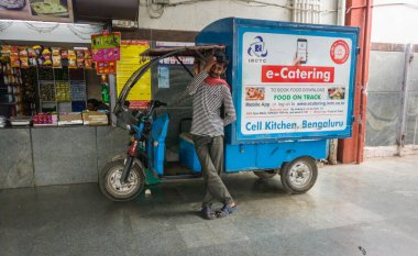 Bangalore, Karnataka, Hindistan - Ocak 2020: E-servis arabasının yanında duran bir adam, Hint Demiryolları 'ndan yolculara çevrimiçi yemek siparişi dağıtıyor.