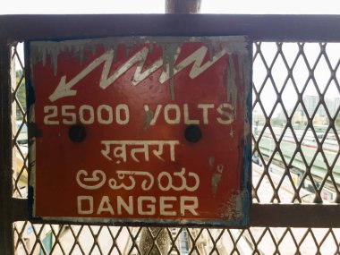 Bangalore, Karnataka, Hindistan - Ocak 2020: Kırmızı Tehlike tabelası yayaları bir tren istasyonundaki yüksek voltaj hakkında uyardı.