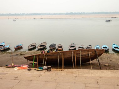Varanasi, Uttar Pradesh, Hindistan - Şubat 2015: Eski şehrin eski ghatlarında, Ganga nehrinin kıyısında boşta duran küçük kayıkları olan büyük ahşap bir tekne yapım aşamasında..