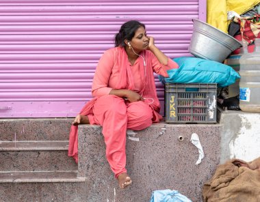 Chennai, Tamil Nadu, Hindistan - Ağustos 2018: Düşüncelere dalmış yol kenarında oturan genç Hintli bir kadının samimi bir portresi.
