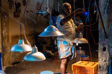Chennai, Tamil Nadu, Hindistan - Ağustos 2018: Hintli bir adam Georgetown 'daki elektrik dükkanında elektrik ampullerinin kablolarını tamir ediyor.