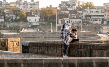 Nagpur, Maharahstra, Hindistan - Mart 2019: Futala gölünde dinlenen iki genç Hintli kadın.