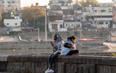 Nagpur, Maharahstra, Hindistan - Mart 2019: Göl kenarındaki akıllı telefonlarına bakan iki genç Hintli kadın.