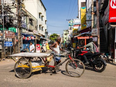 Trichy, Tamil Nadu, Hindistan - Şubat 2020: Tekerlekli arabasıyla Tiruchirappalli pazarında yürüyen yaşlı bir Hintli işçi.