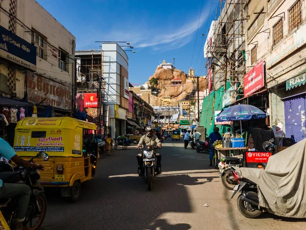 Trichy, Tamil Nadu, Hindistan - Şubat 2020: Çorak bir tepenin üzerindeki antik Rock Fort Tapınağı 'na giden pazar caddesinde trafik.