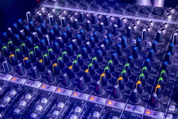 Analog studio sound mixer closeup with laptop and sound wave form in the background.