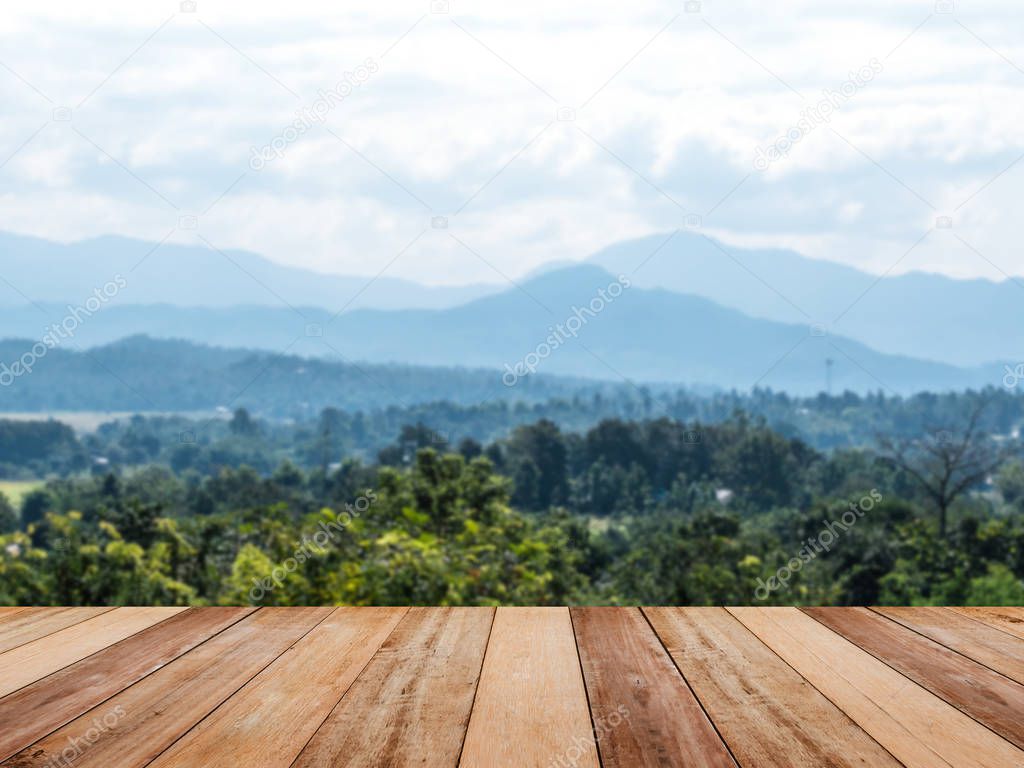 Wood table top over mountain and tropical forest landscape with blue sky background. Montage style to display the product.